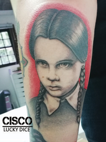 Tatouage couleur tête du personnage Mercredi de la famille Adams réalisé par Cisco Lucky Dice Tattoo